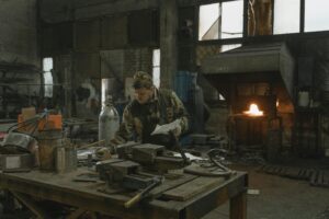 Atelier de sculpture métal avec artisan travaillant le fer et créant une œuvre animalière.